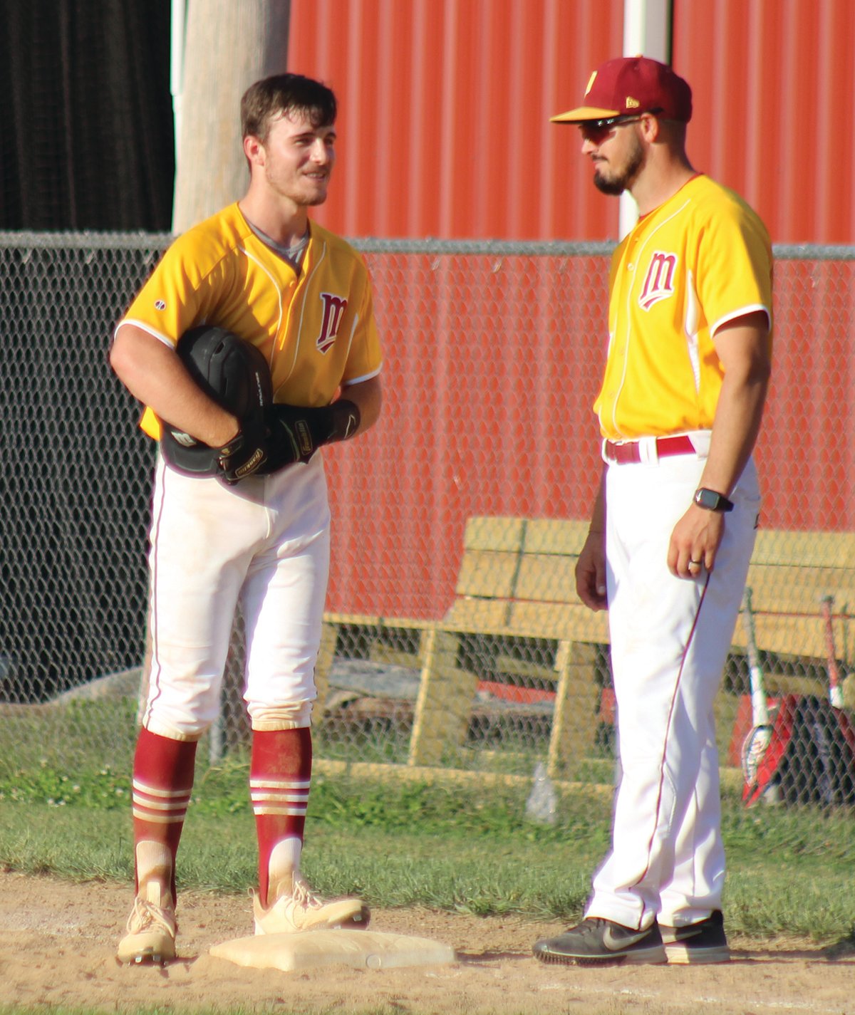 Mansfield’s Trevor Williams reaches base in the Lions’ win over Norwood last week. First base coach Drew Ames visits with his new baserunner.